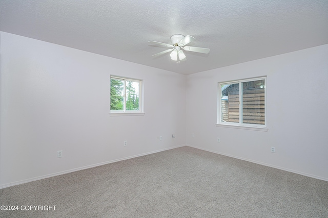 spare room featuring carpet floors, a textured ceiling, baseboards, and a ceiling fan