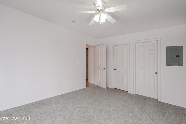 unfurnished bedroom with carpet floors, ceiling fan, electric panel, and baseboards