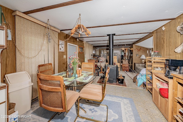 dining space featuring a wood stove, wood walls, and tile patterned floors