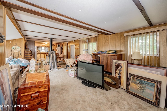 carpeted living room with beamed ceiling and wooden walls