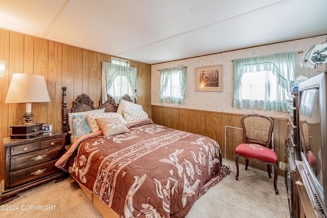 bedroom with a wainscoted wall, carpet floors, wood walls, and multiple windows