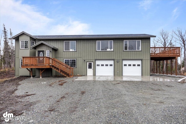 raised ranch with gravel driveway, an attached garage, stairs, and a deck