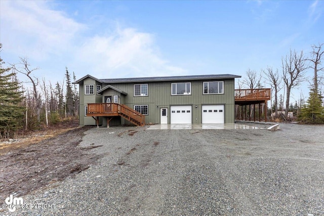 view of front of property with a garage, driveway, a wooden deck, and stairs