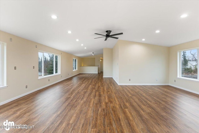 unfurnished living room featuring plenty of natural light, wood finished floors, and baseboards