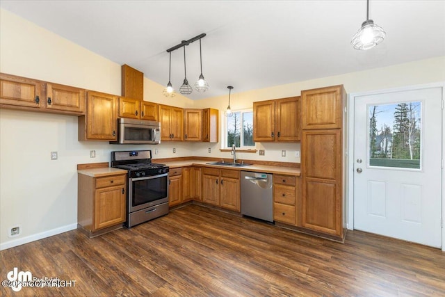 kitchen with vaulted ceiling, appliances with stainless steel finishes, a sink, and brown cabinets