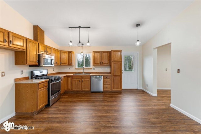 kitchen with lofted ceiling, appliances with stainless steel finishes, dark wood-type flooring, hanging light fixtures, and a sink