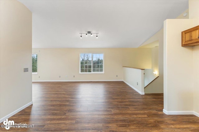 empty room featuring lofted ceiling, dark wood finished floors, and baseboards