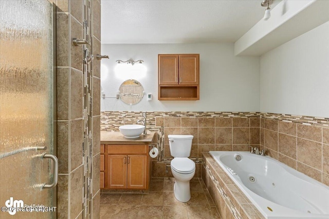 full bathroom featuring tile walls, toilet, a shower stall, vanity, and a tub with jets