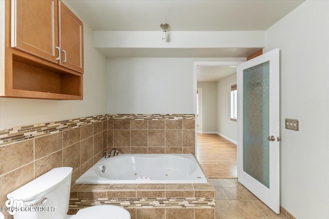 bathroom with tile patterned floors, toilet, and a tub with jets