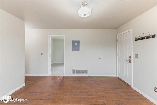 spare room featuring baseboards, hardwood / wood-style flooring, visible vents, and electric panel