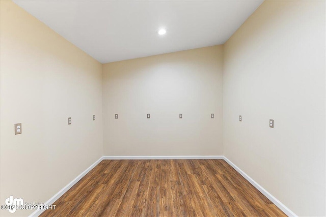 spare room with baseboards and wood finished floors