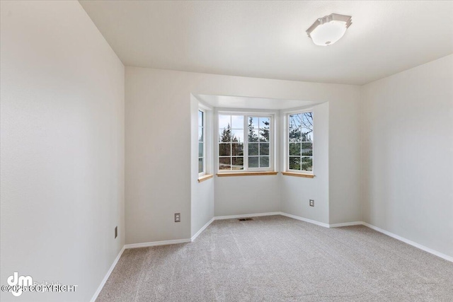 carpeted spare room with visible vents and baseboards