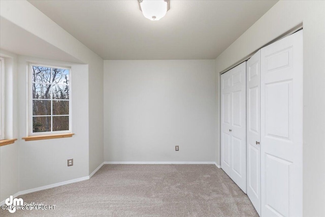 unfurnished bedroom with carpet floors, a closet, and baseboards