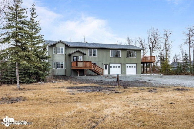 raised ranch featuring an attached garage, driveway, stairway, and a deck