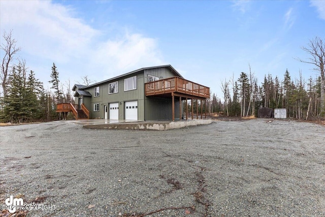 rear view of house featuring an attached garage and a wooden deck