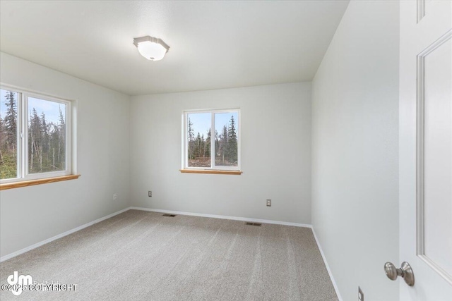 empty room featuring carpet flooring, visible vents, and baseboards