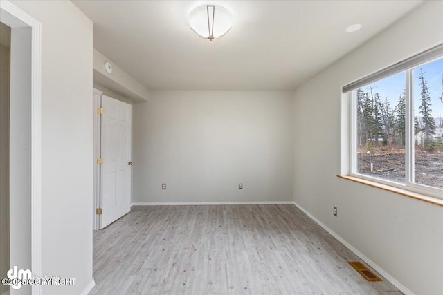 empty room featuring visible vents, baseboards, and wood finished floors