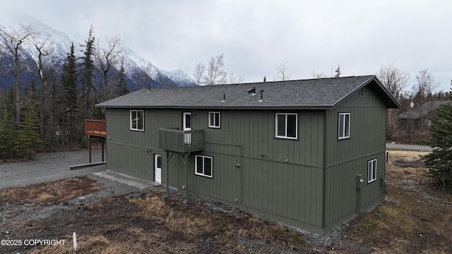 rear view of property with roof with shingles and a wooden deck