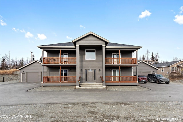 view of front of house with a garage, aphalt driveway, an outbuilding, and a balcony