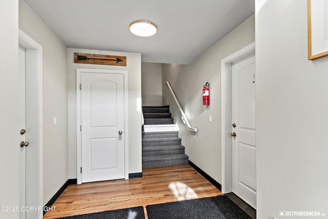 foyer entrance with baseboards, stairway, and light wood-style floors