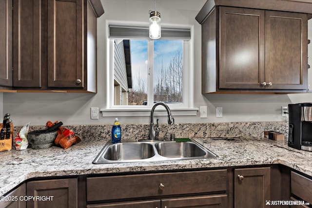 kitchen with a sink, hanging light fixtures, and dark brown cabinets