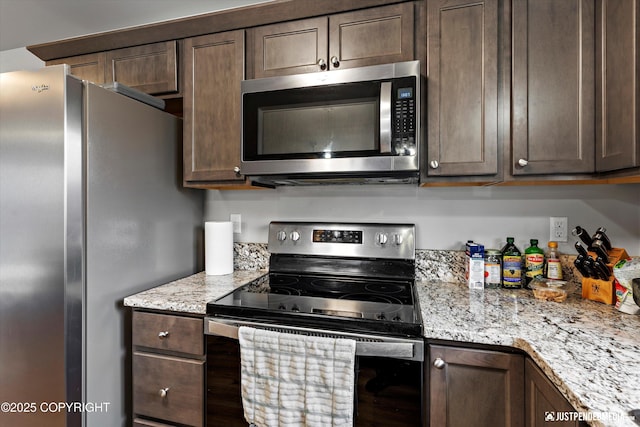 kitchen with appliances with stainless steel finishes, light stone counters, and dark brown cabinets