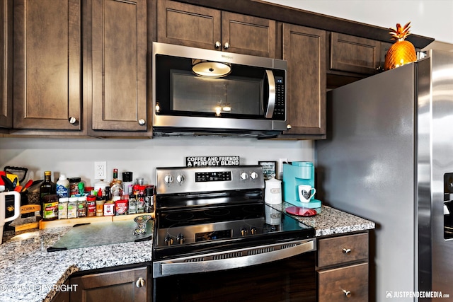 kitchen with stainless steel appliances, dark brown cabinets, and light stone countertops