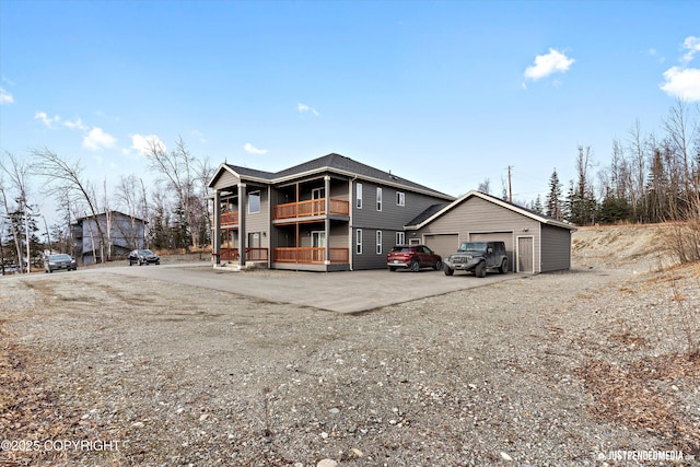 view of front of home with a garage, a balcony, and an outbuilding