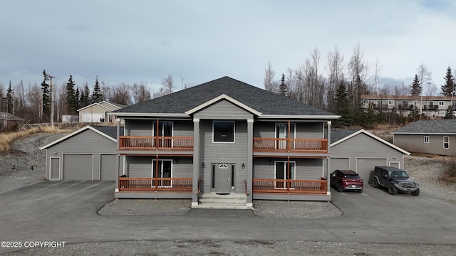 view of front of home with a balcony, roof with shingles, and an outdoor structure