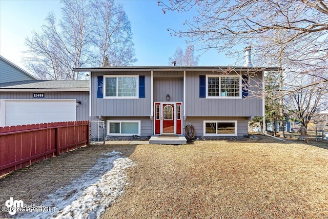 split foyer home with a garage, a front yard, and fence