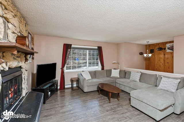 living room with a fireplace, a textured ceiling, a baseboard heating unit, and wood finished floors