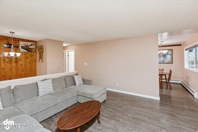 living area with an inviting chandelier, wood finished floors, baseboards, and a textured ceiling