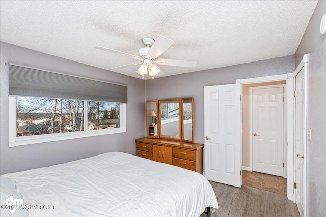 bedroom featuring a textured ceiling, a ceiling fan, and wood finished floors