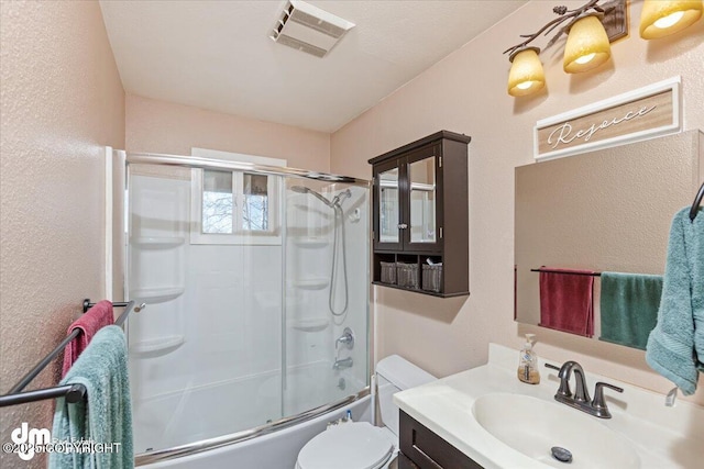 bathroom featuring visible vents, toilet, a textured wall, combined bath / shower with glass door, and vanity