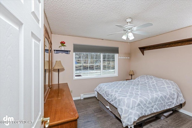 bedroom featuring a textured ceiling, wood finished floors, baseboards, and a baseboard radiator