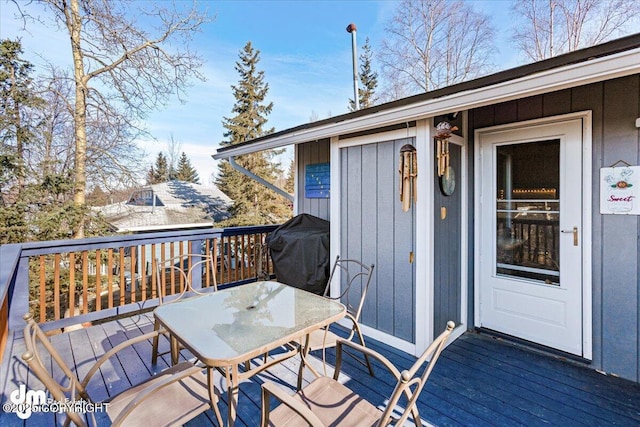 wooden deck with outdoor dining space and area for grilling