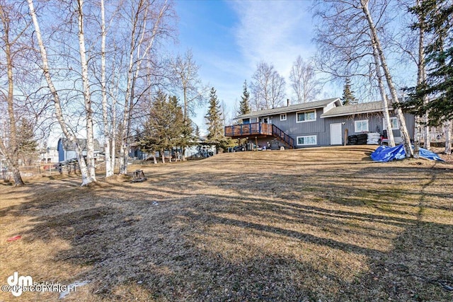 back of property with a yard, a deck, and stairs