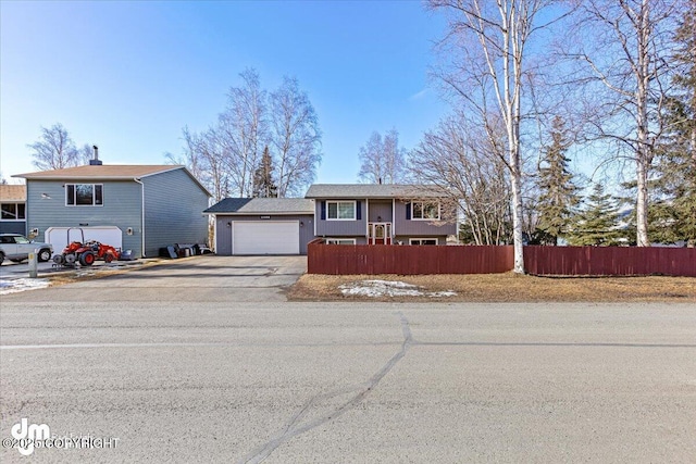 view of front of home featuring a fenced front yard, a garage, and aphalt driveway