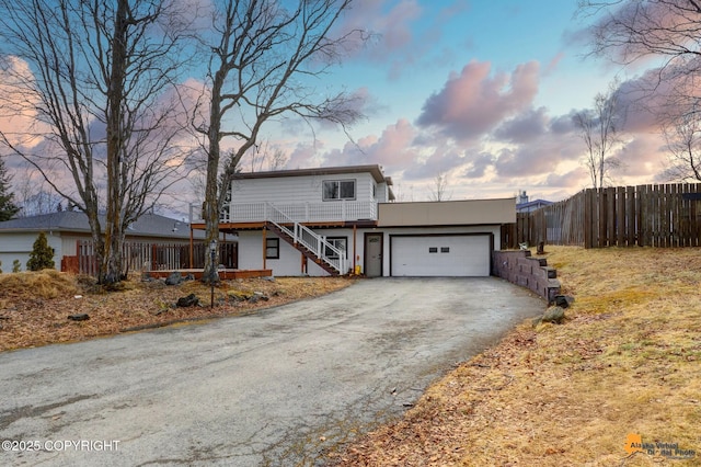 view of front of property featuring aphalt driveway, stairway, an attached garage, and fence