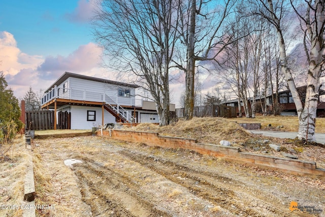 view of yard with stairway, an attached garage, a wooden deck, and fence