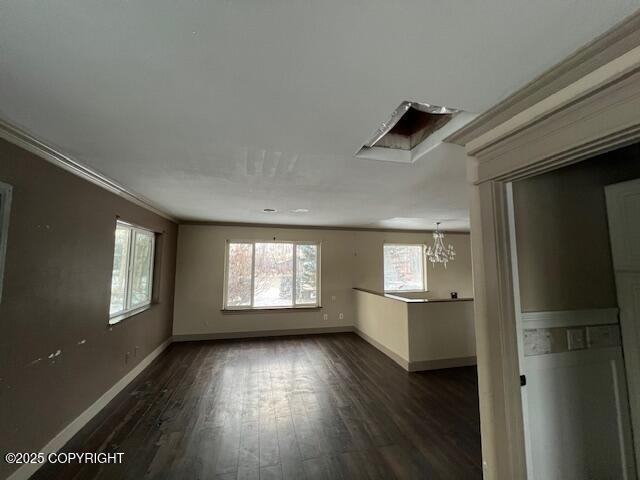 spare room featuring dark wood-style floors, baseboards, a chandelier, and crown molding