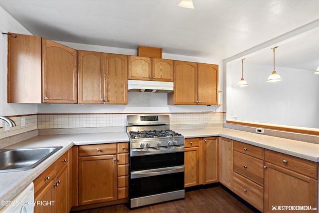 kitchen with under cabinet range hood, double oven range, a sink, light countertops, and dishwasher