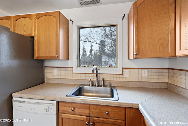 kitchen featuring light countertops, visible vents, white dishwasher, and a sink