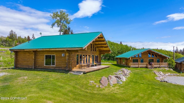 rear view of property featuring a deck, metal roof, a yard, and log exterior