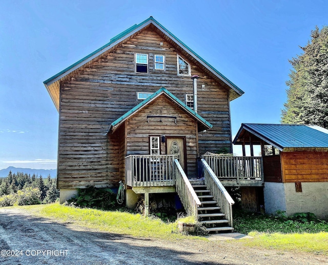 view of front facade with a deck with mountain view, stairway, and metal roof