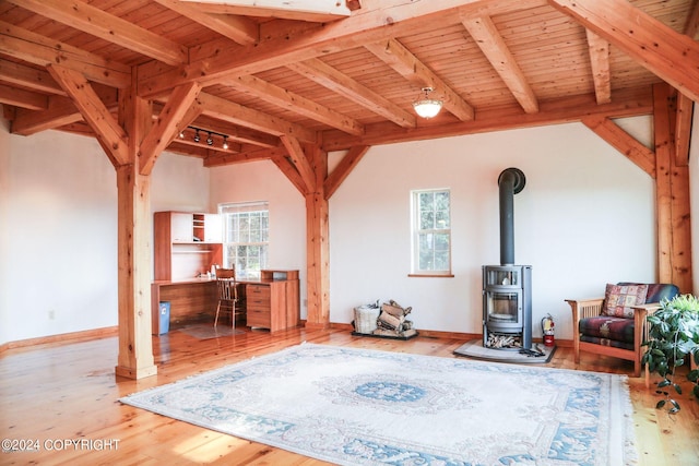 living area featuring a wood stove, wooden ceiling, a wealth of natural light, and beamed ceiling