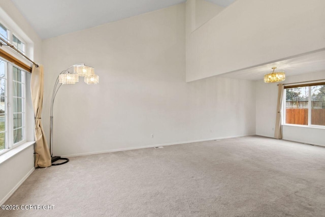 unfurnished room with a chandelier, high vaulted ceiling, carpet flooring, and baseboards