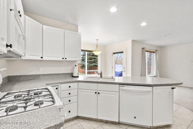 kitchen featuring white appliances, white cabinetry, a sink, and a peninsula