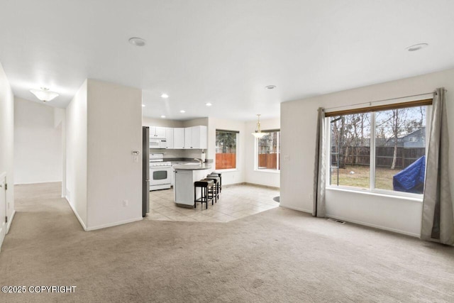 unfurnished living room featuring recessed lighting, baseboards, a sink, and light colored carpet