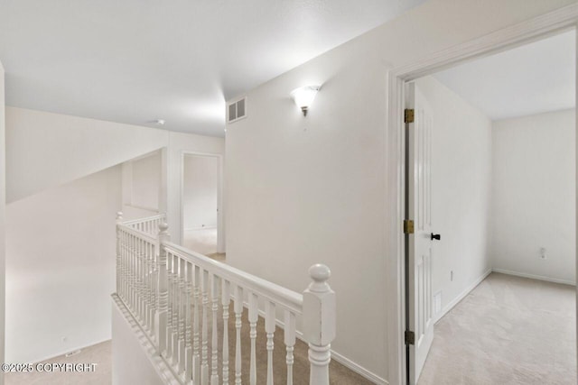 hallway with visible vents, carpet floors, an upstairs landing, and baseboards